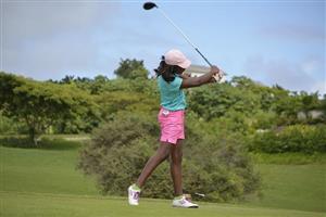 Female golfer in bright clothes finishing her swing.