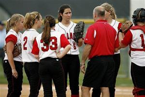 Softball team conferring with their coach during a game.